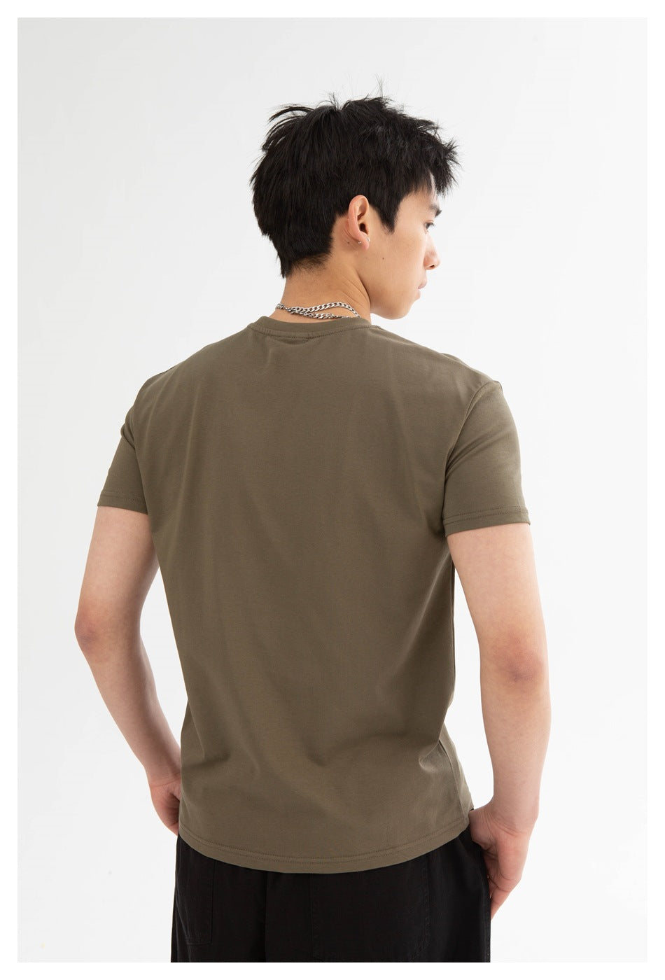 Rear view of a model wearing an olive-brown short-sleeve crew-neck T-shirt with black pants.