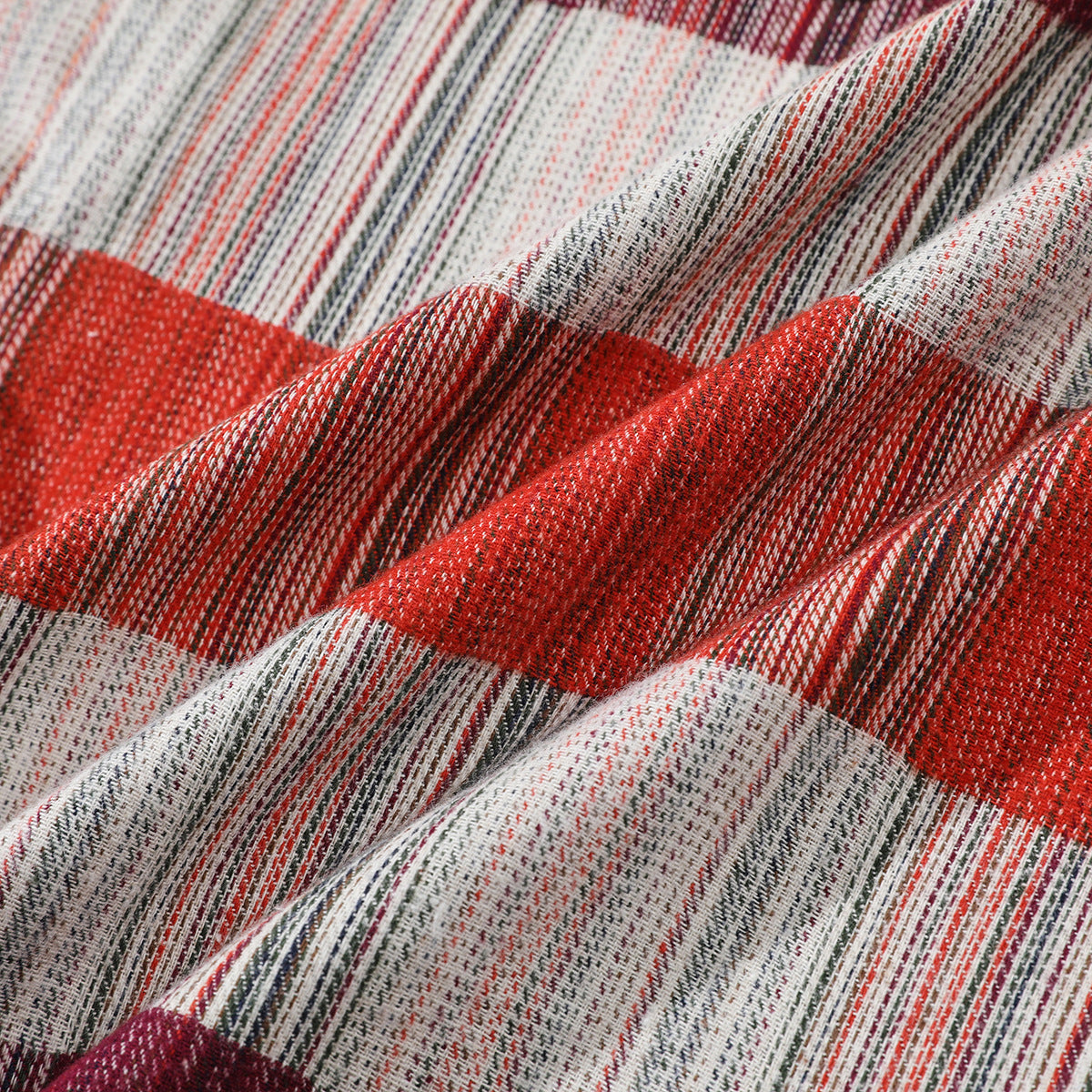Close-up of red, burgundy, cream and dark plaid fabric gathered into soft folds.