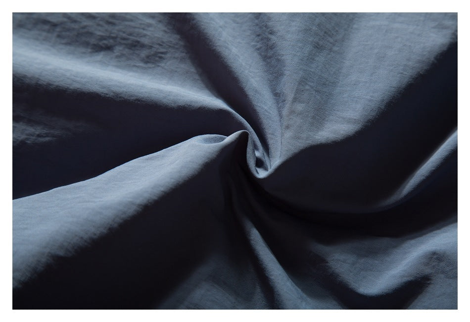Extreme close-up of blue-gray garment fabric gathered into folds.