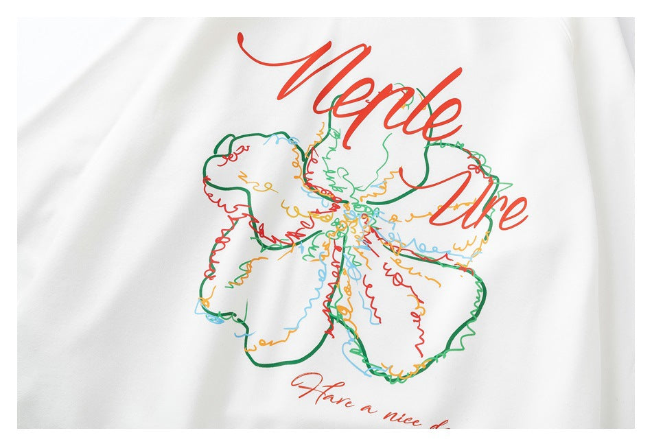 Close-up of a white sweatshirt with a colorful outlined flower and red cursive lettering printed on the front.