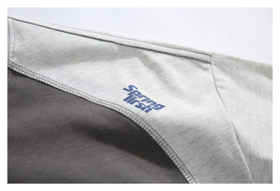 Close-up of a light gray and charcoal color-block garment with a blue printed wordmark and curved seam.