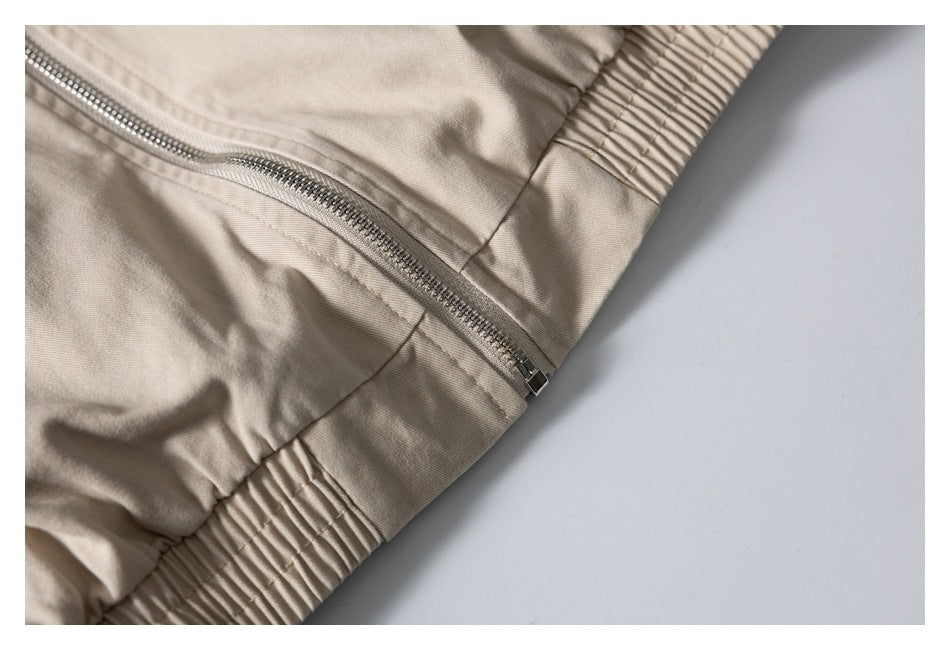 Close-up of a beige jacket's metal zipper and gathered elastic hem.