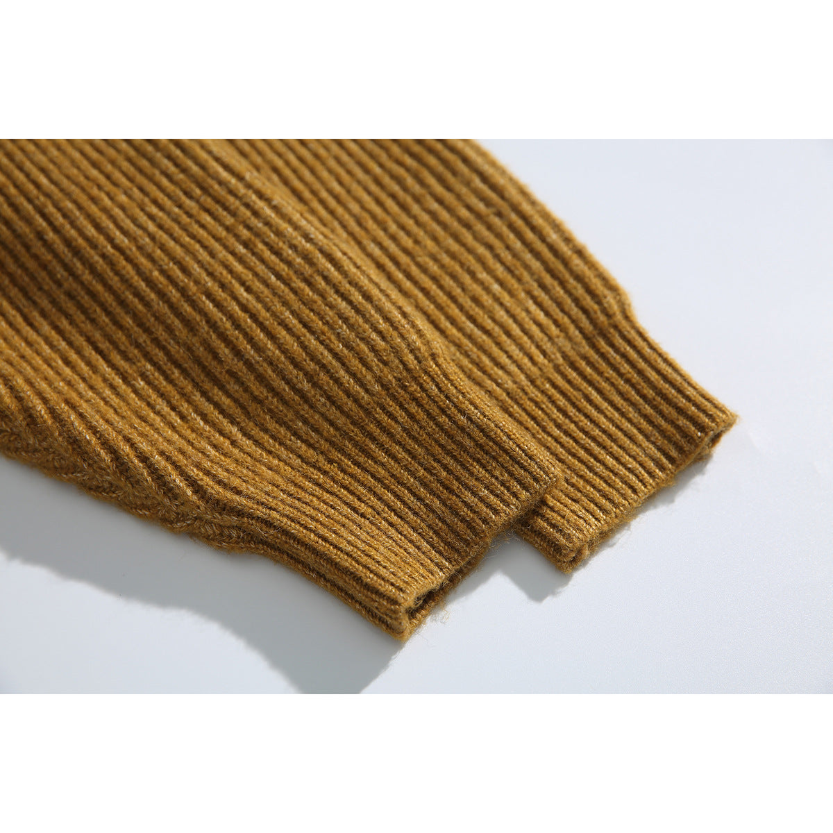 Close-up of the ribbed sleeve and cuff of a mustard-brown cardigan.
