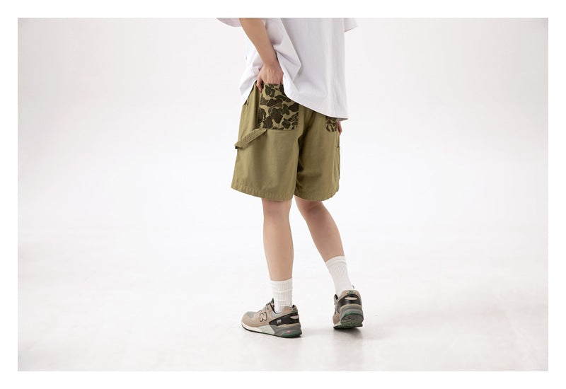 Rear three-quarter view of a model wearing khaki shorts with dark camouflage-print pockets.