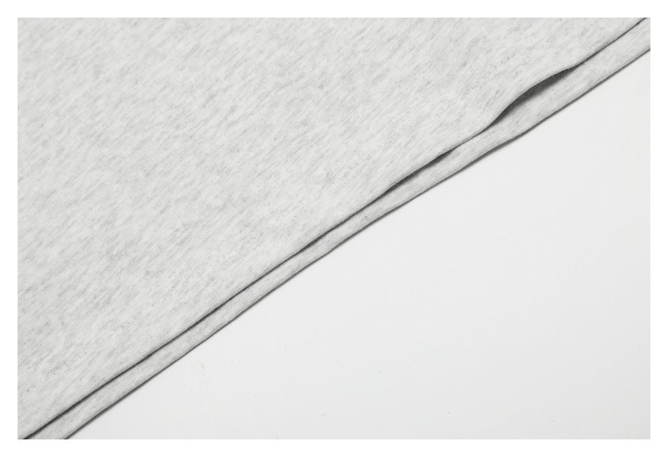 Close-up of light heather gray fabric with a folded edge against a white background.