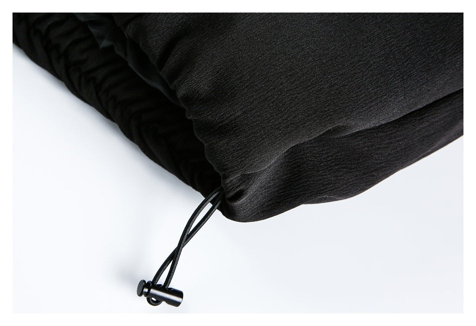 Close-up of a black garment hem with an adjustable drawcord and toggle.