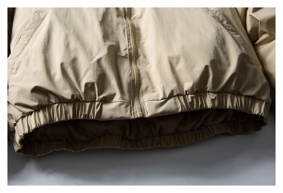 Close-up of a beige jacket's front zipper and gathered elastic hem.