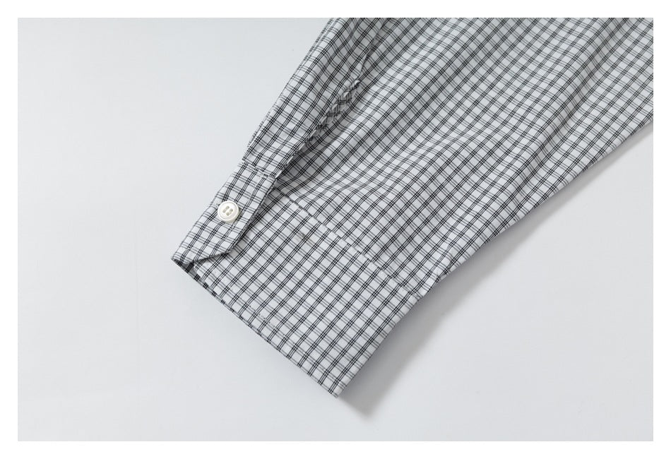 Close-up of a black-and-gray checked shirt sleeve cuff with a white button.