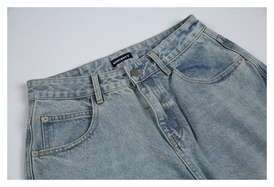 Partial front view of light blue washed jeans, showing the waistband, button, fly, and front pockets.