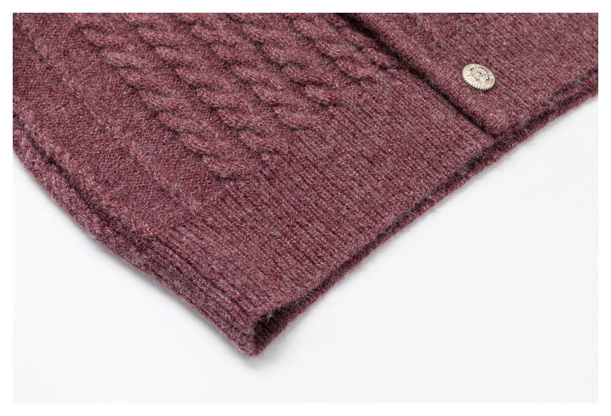 Close-up of the burgundy knit garment's ribbed hem and a decorative metallic button.
