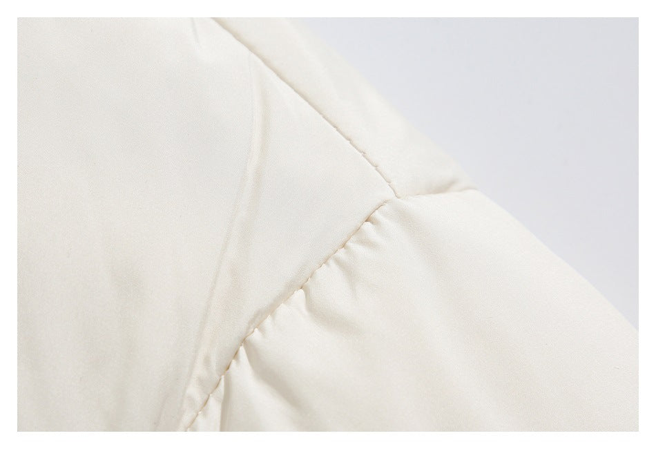 Close-up of the cream jacket shoulder seam and sleeve join.