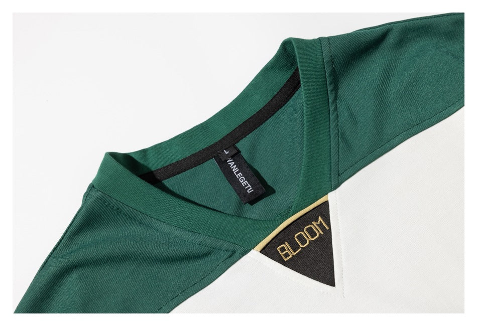 Close-up of the green shirt's V-neck, inner label, white panel, and embroidered BLOOM patch.