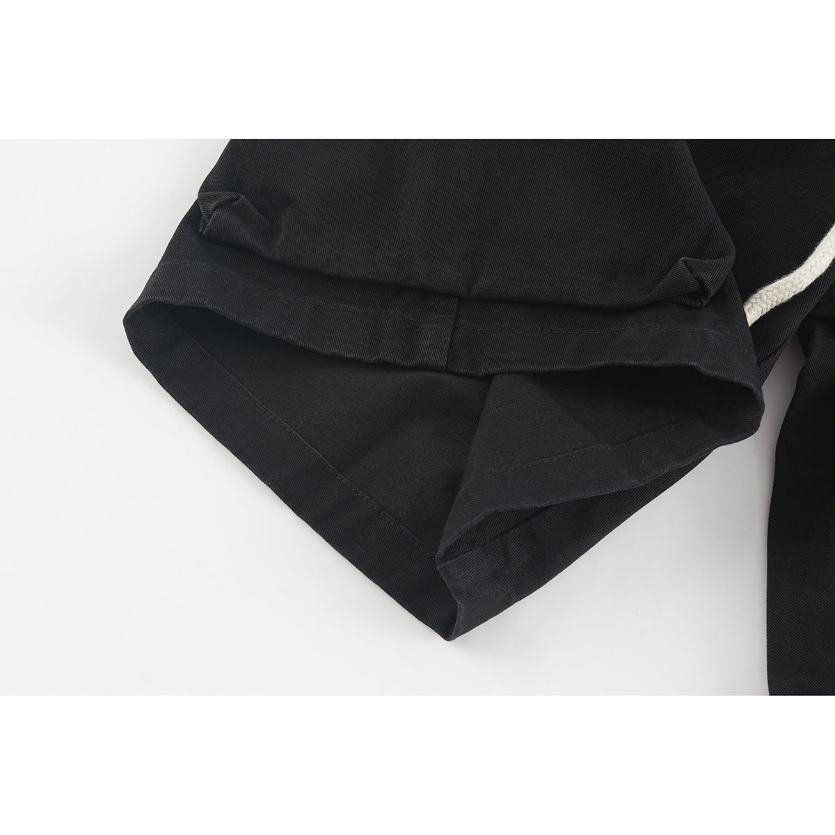 Close-up of the folded hem and stitching on black shorts.