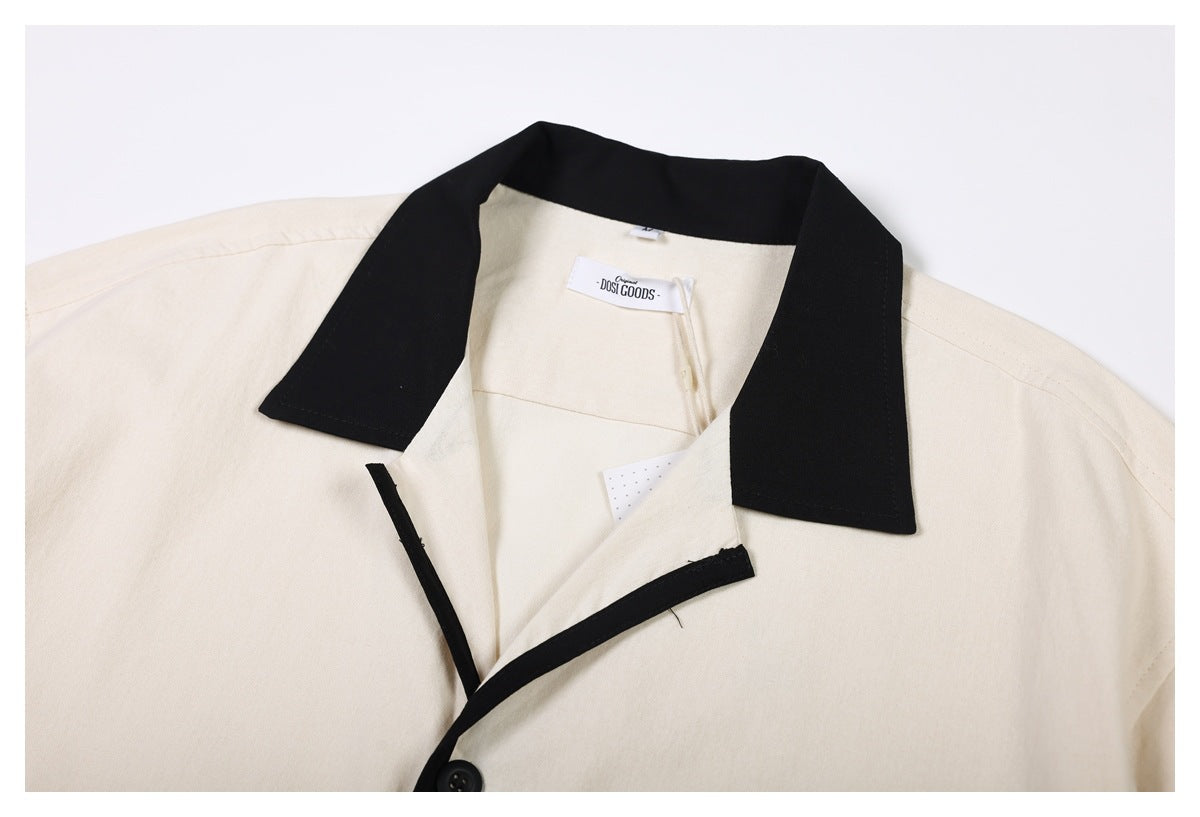 Close-up of a cream shirt's wide black collar, black-edged placket, and sewn-in neck label.