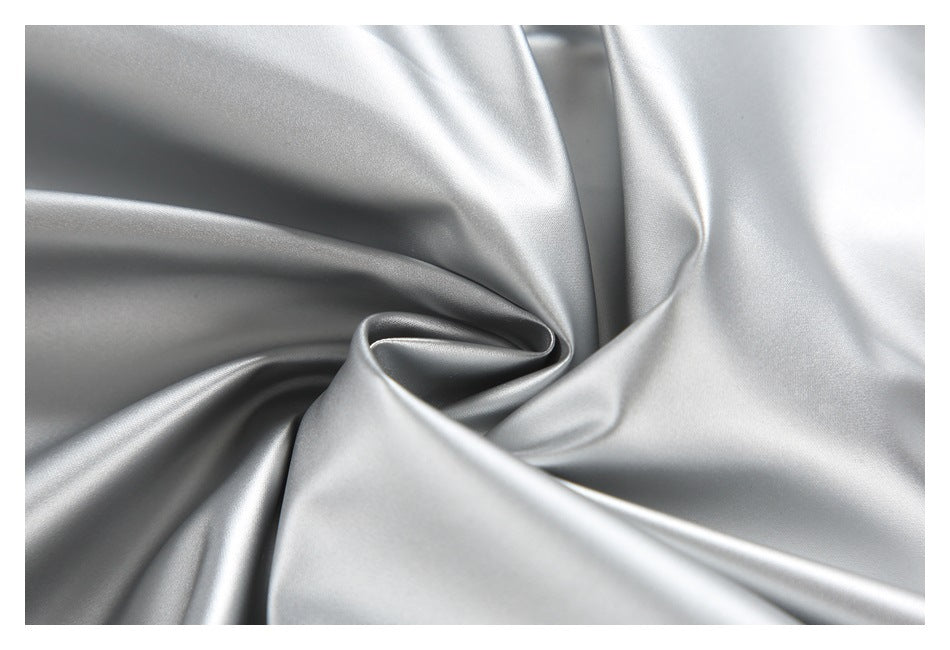 Close-up of glossy silver fabric arranged in soft folds.