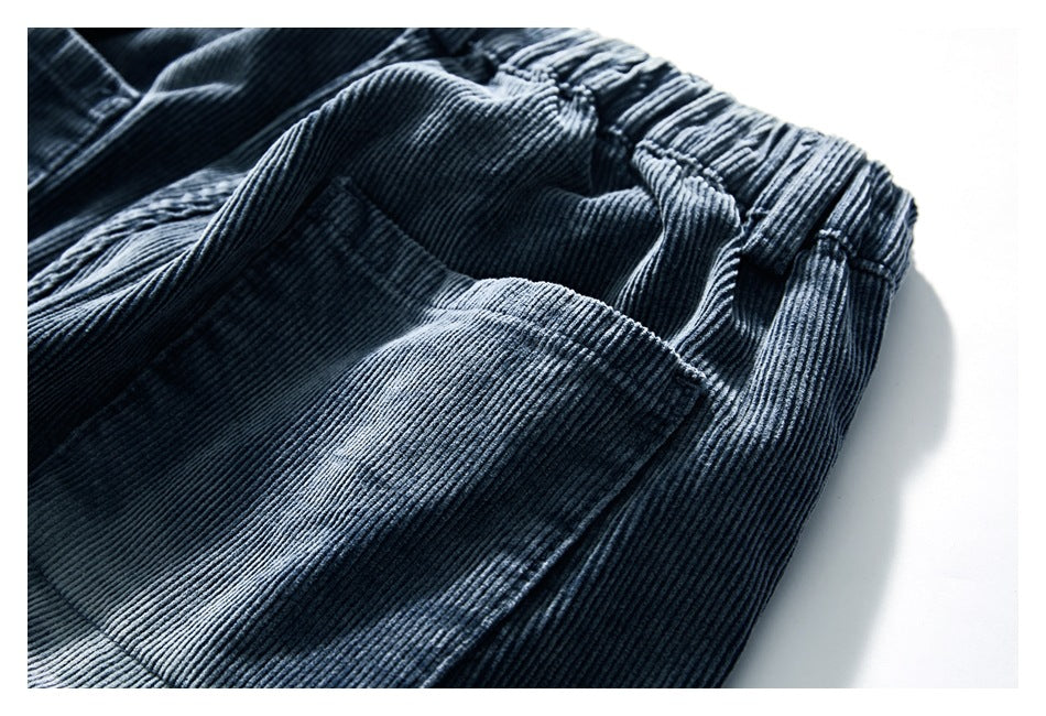 Close-up of blue-gray corduroy pants showing a gathered waistband and front pocket.