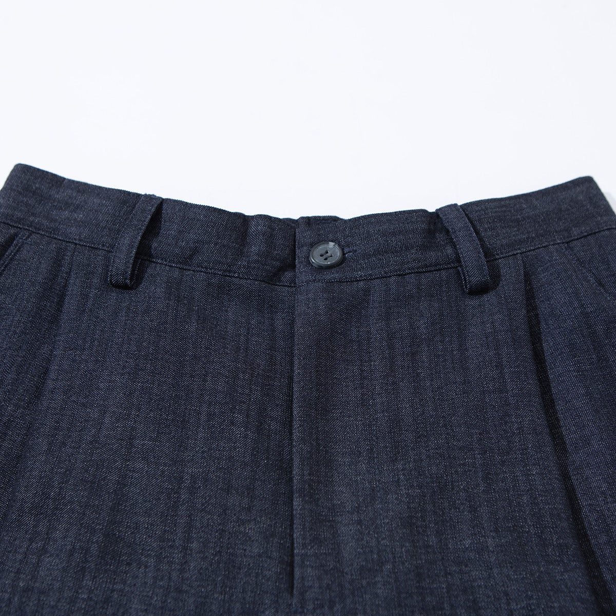 Close-up of dark navy shorts showing the buttoned waistband, belt loops and front pleats.