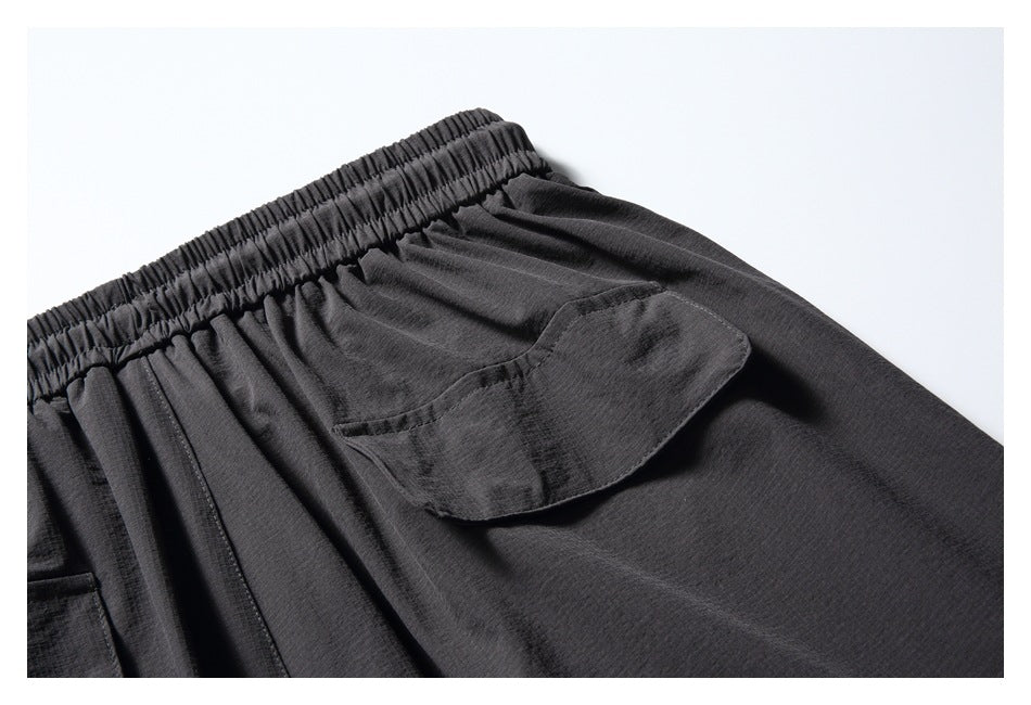 Close-up of charcoal pants showing an elastic waistband and a flap cargo pocket.