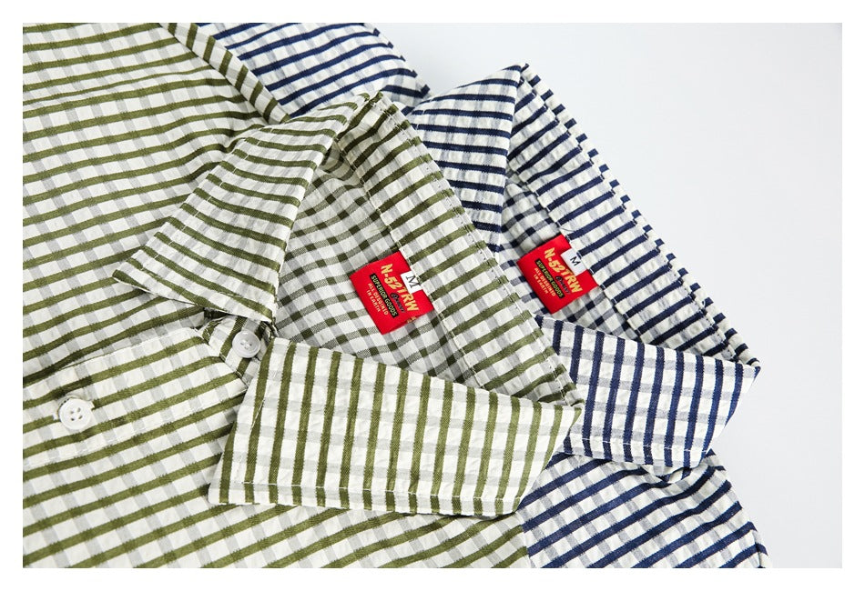 Close-up of olive and navy striped short-sleeve shirts folded together, showing their collars, buttons and labels.