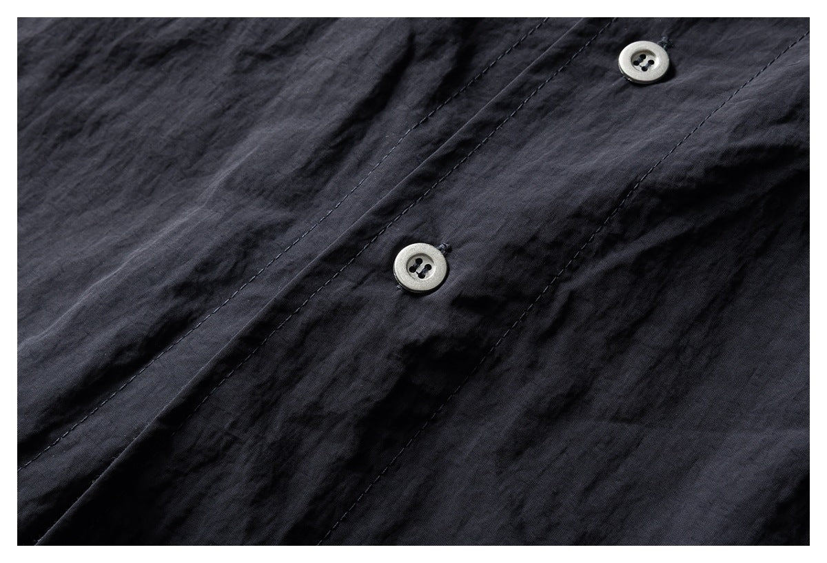 Extreme close-up of two pale buttons on the dark shirt's stitched button placket.
