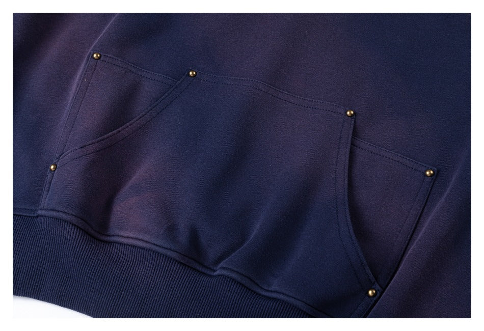 Close-up of the navy sweatshirt's large front pocket with angled openings and small gold-tone studs.