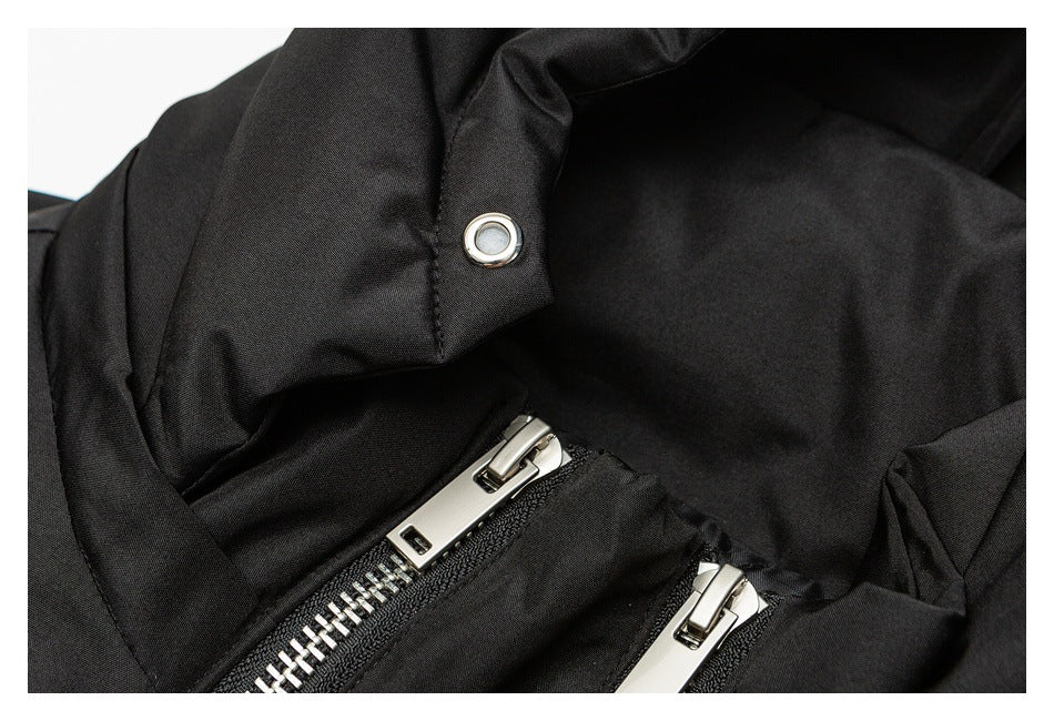 Close-up of a black jacket with a metal snap and two silver zippers.