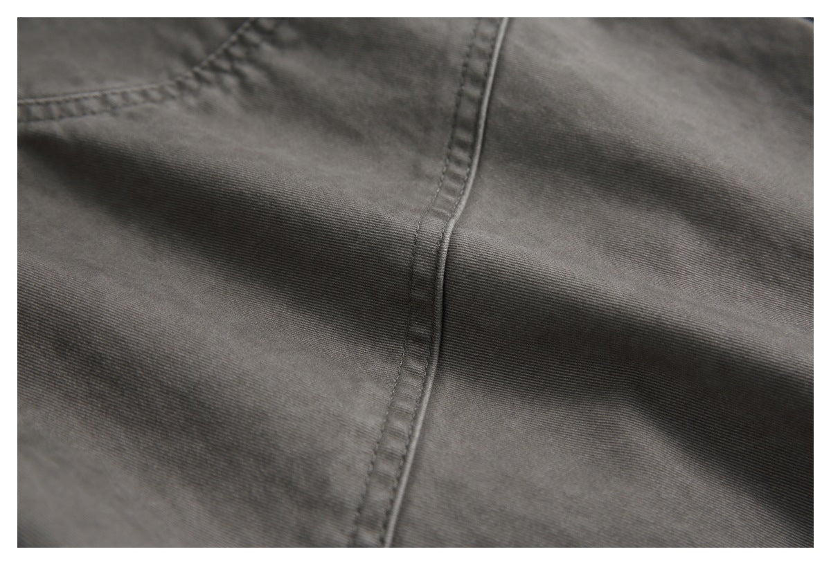 Close-up of charcoal-gray garment fabric and a stitched seam.