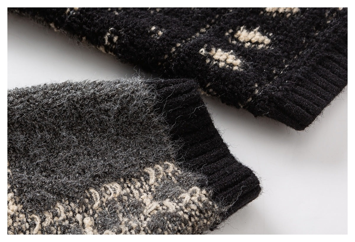 Close-up of black and charcoal knit fabric with cream geometric motifs and a ribbed edge.