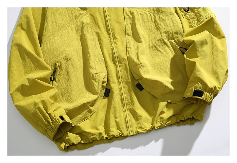 Cropped front view of a bright yellow jacket with a center zipper, zip pockets, adjustable cuffs, and elastic hem.