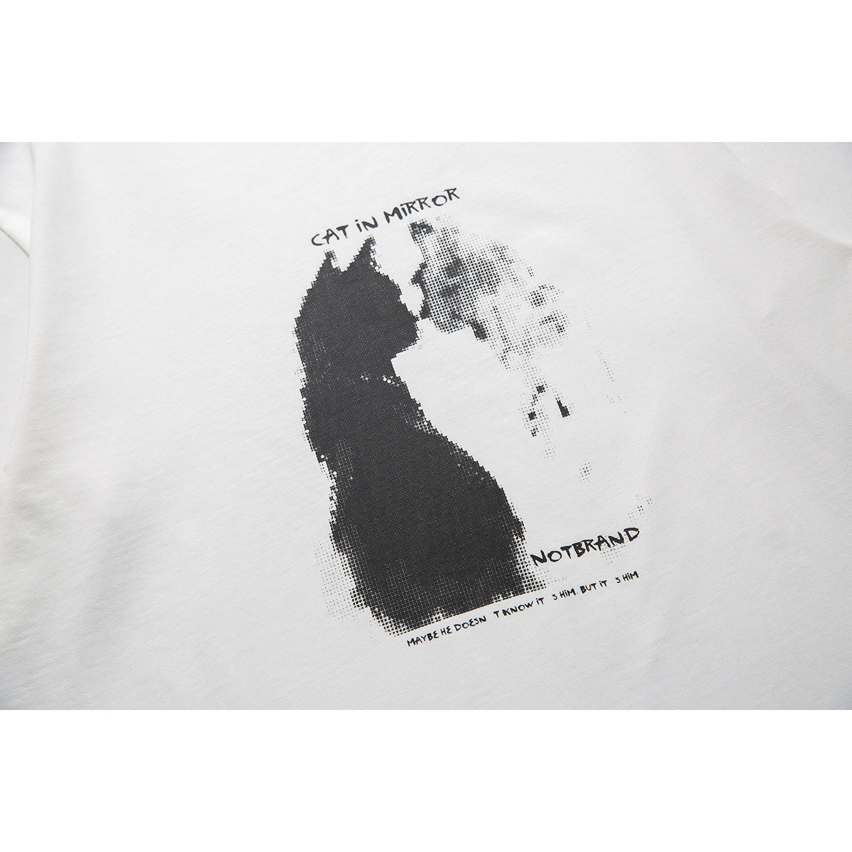 Close-up of a black cat silhouette and its halftone reflection in a graphic printed on a white T-shirt.