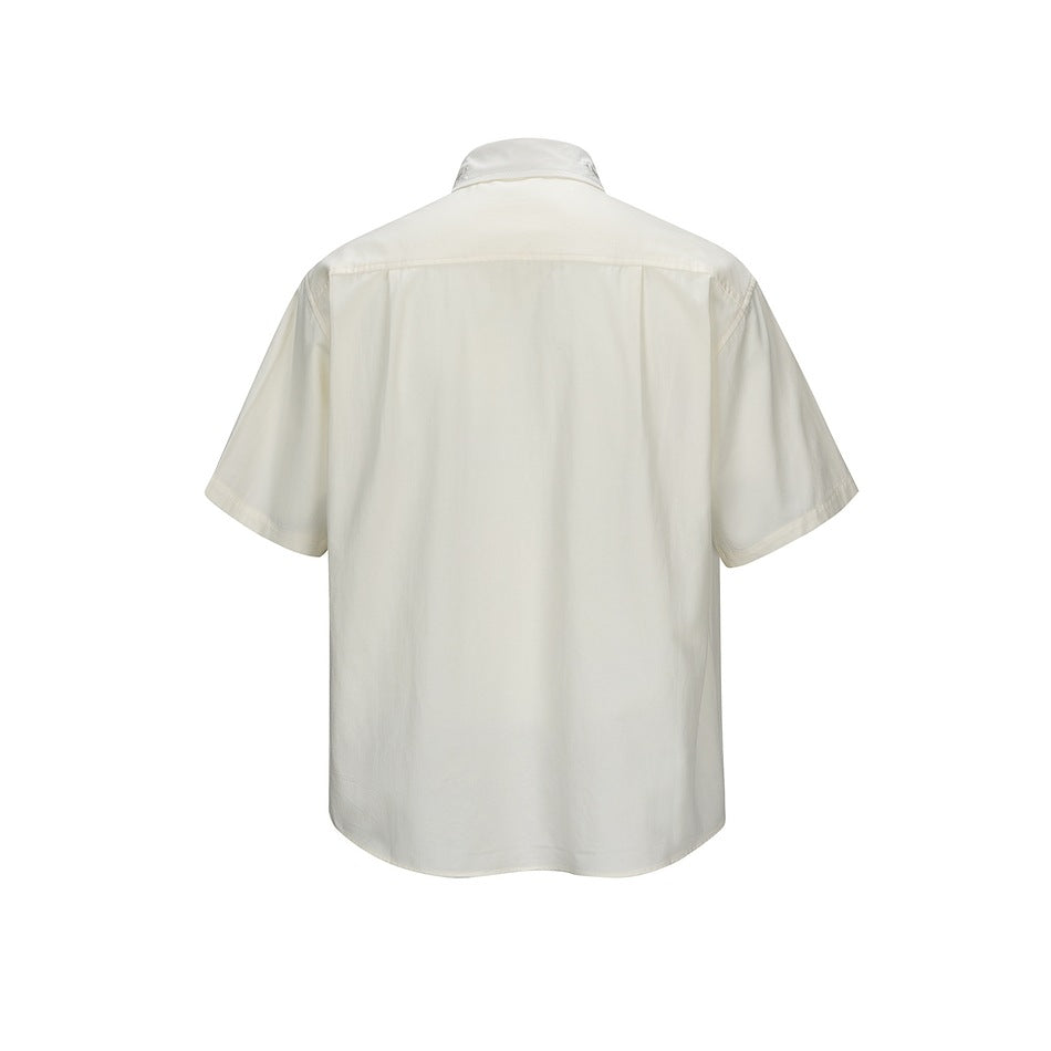 Back view of a beige short-sleeve shirt with a shoulder yoke and pleat below it, shown flat