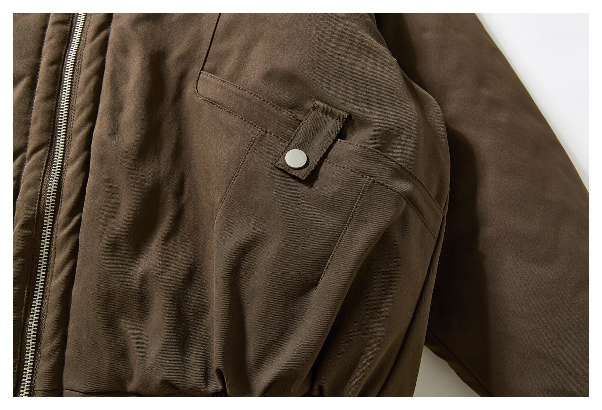 Close-up of a dark brown jacket sleeve pocket with a snap-button flap.