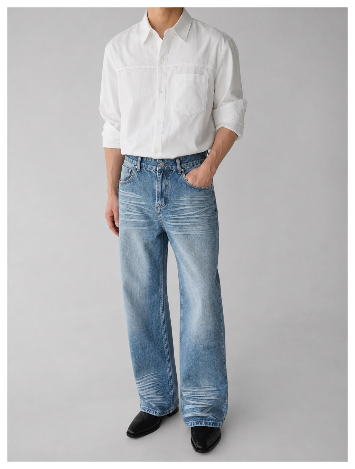 Model wearing light blue wide-leg jeans with a white button-up shirt and black boots, one hand in pocket