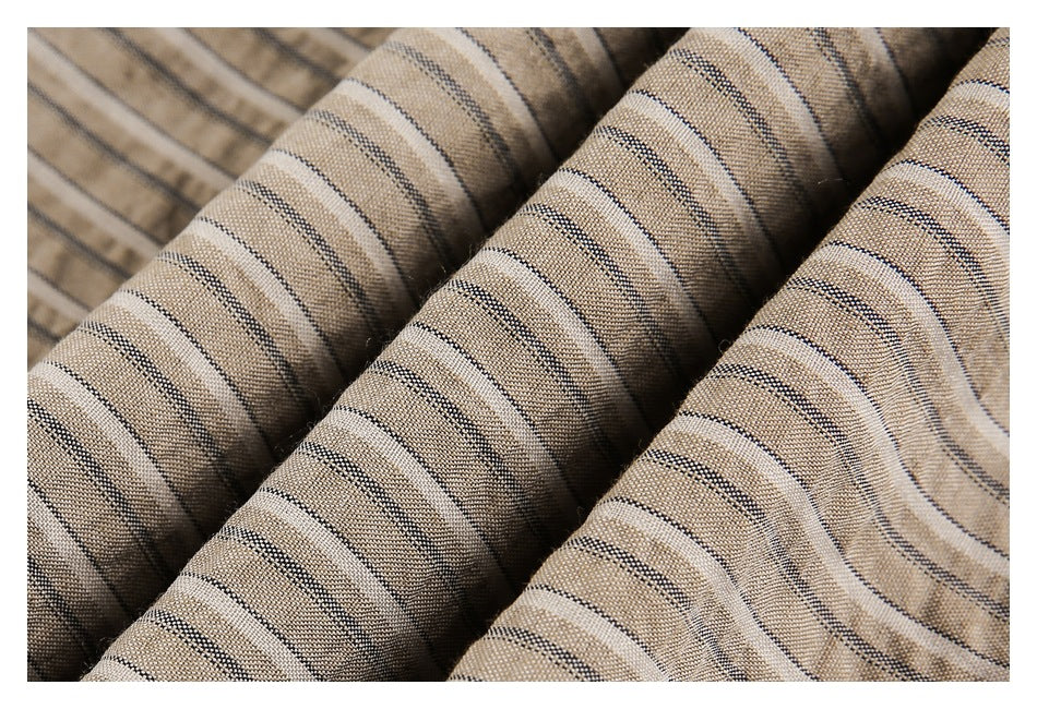 Close-up of beige fabric with narrow dark and light stripes draped in soft folds.