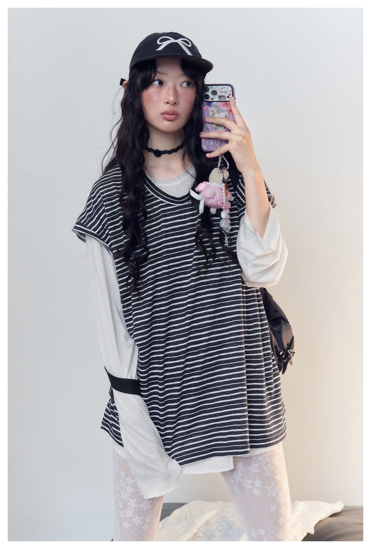 Model in a loose black-and-white striped short-sleeve top layered over a light long-sleeve shirt.