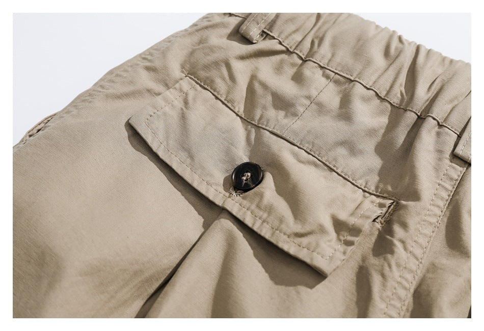 Close-up of a khaki trouser flap pocket with a black button and visible stitching.