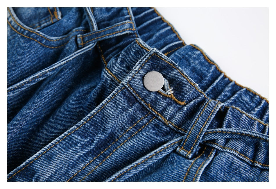 Close-up of blue jeans showing the metal waist button, belt loop, and contrast stitching.