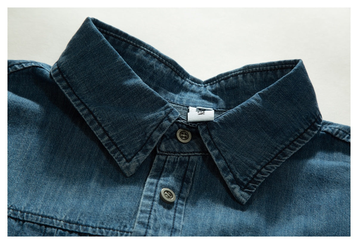 Close-up of a dark blue denim shirt collar, top buttons, and shoulder seams.