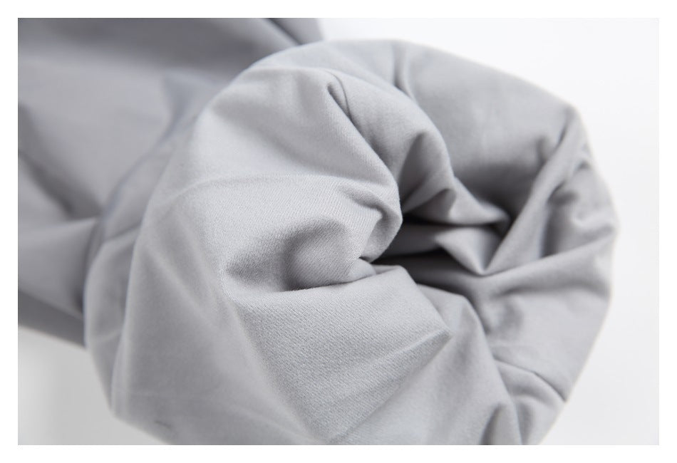 Close-up of the gathered cuff of light gray trousers.