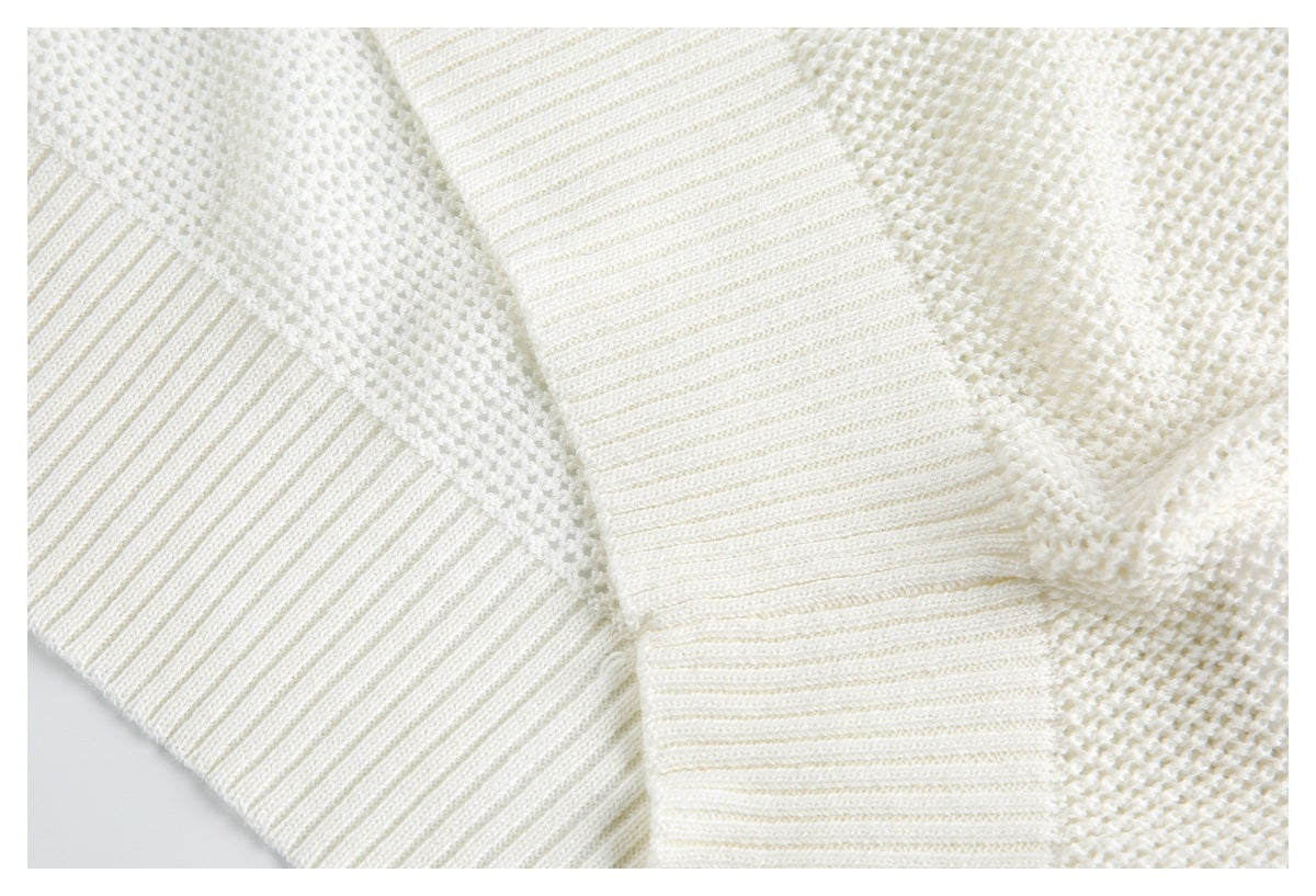 Close-up of an ivory knit sweater with overlapping ribbed cuffs and textured stitches.