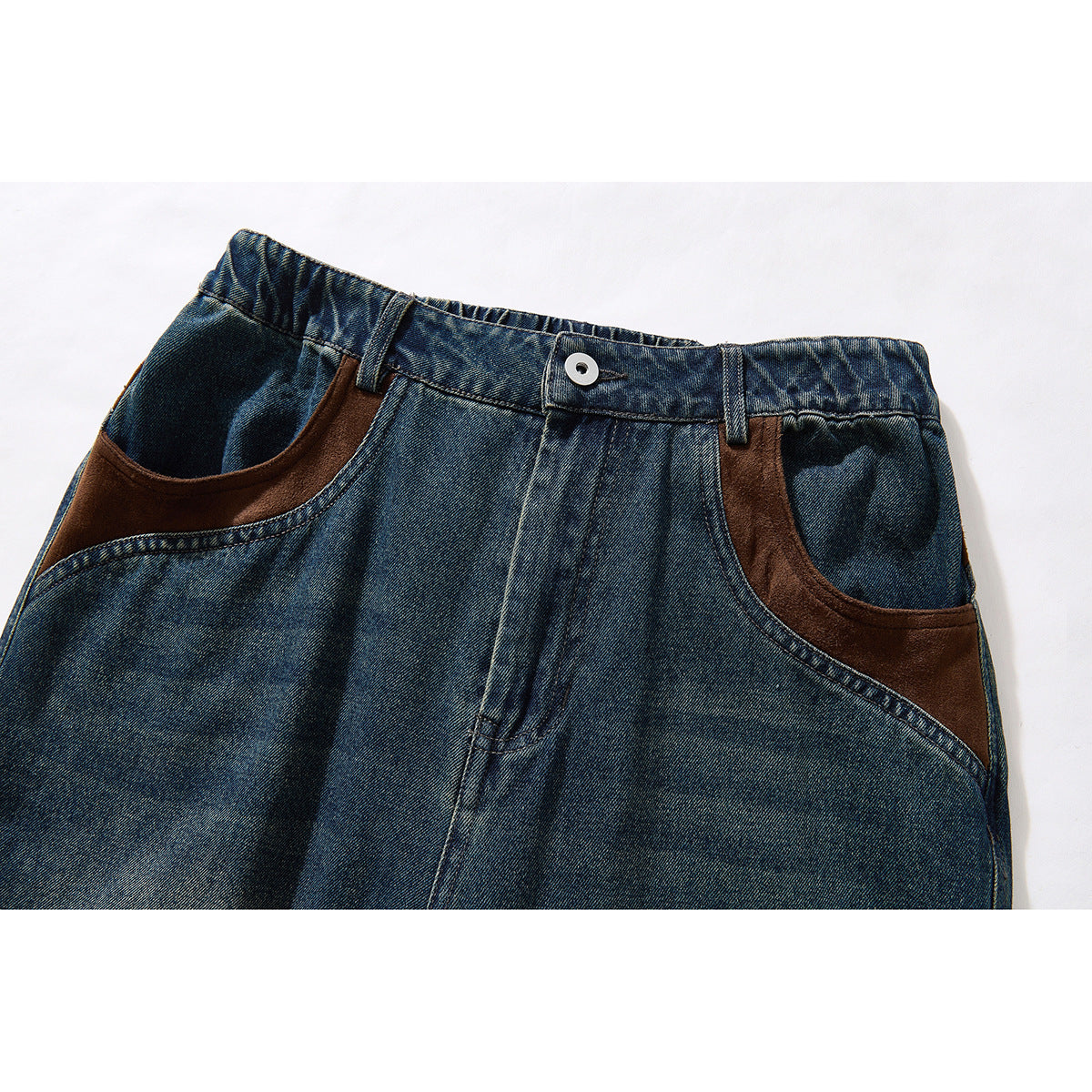 Close-up of blue denim pants showing the front waistband, button, belt loops, and curved pockets with brown trim.