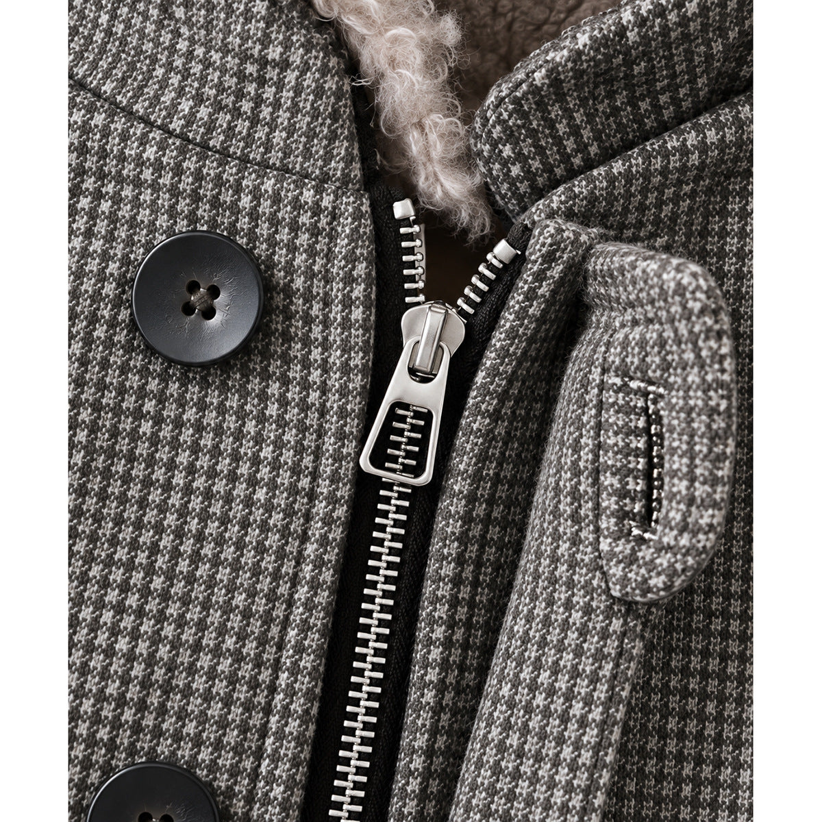 Close-up of the gray patterned jacket showing its large metal zipper, black buttons, and fleece-lined collar.