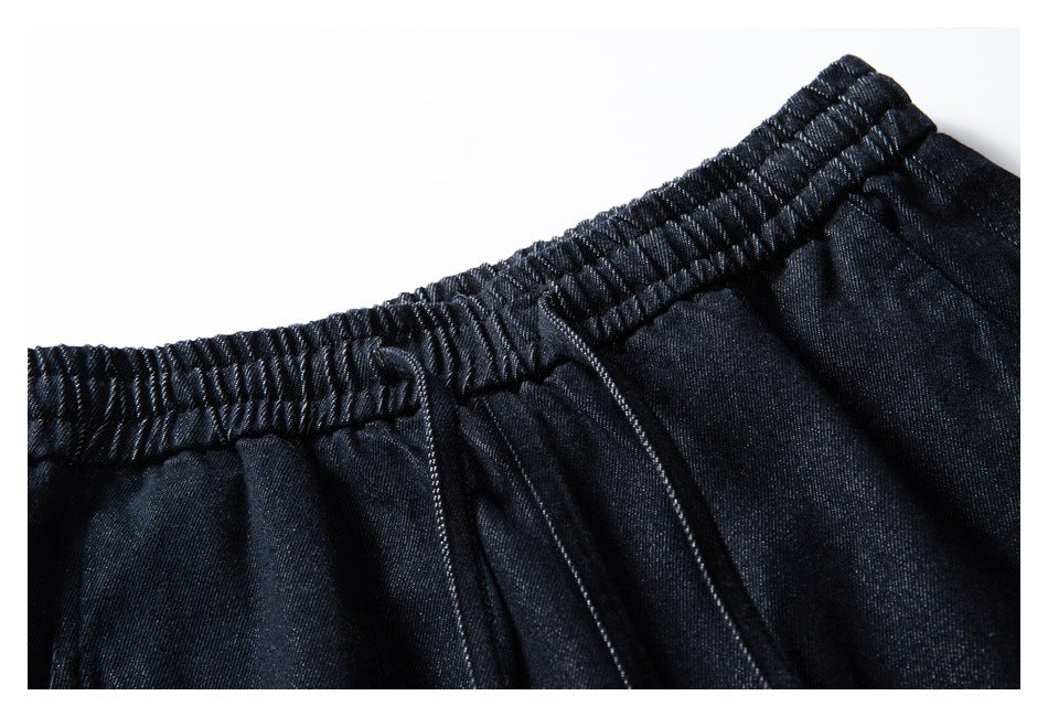 Close-up of dark indigo pants showing the elastic waistband, drawstring, and front seam.
