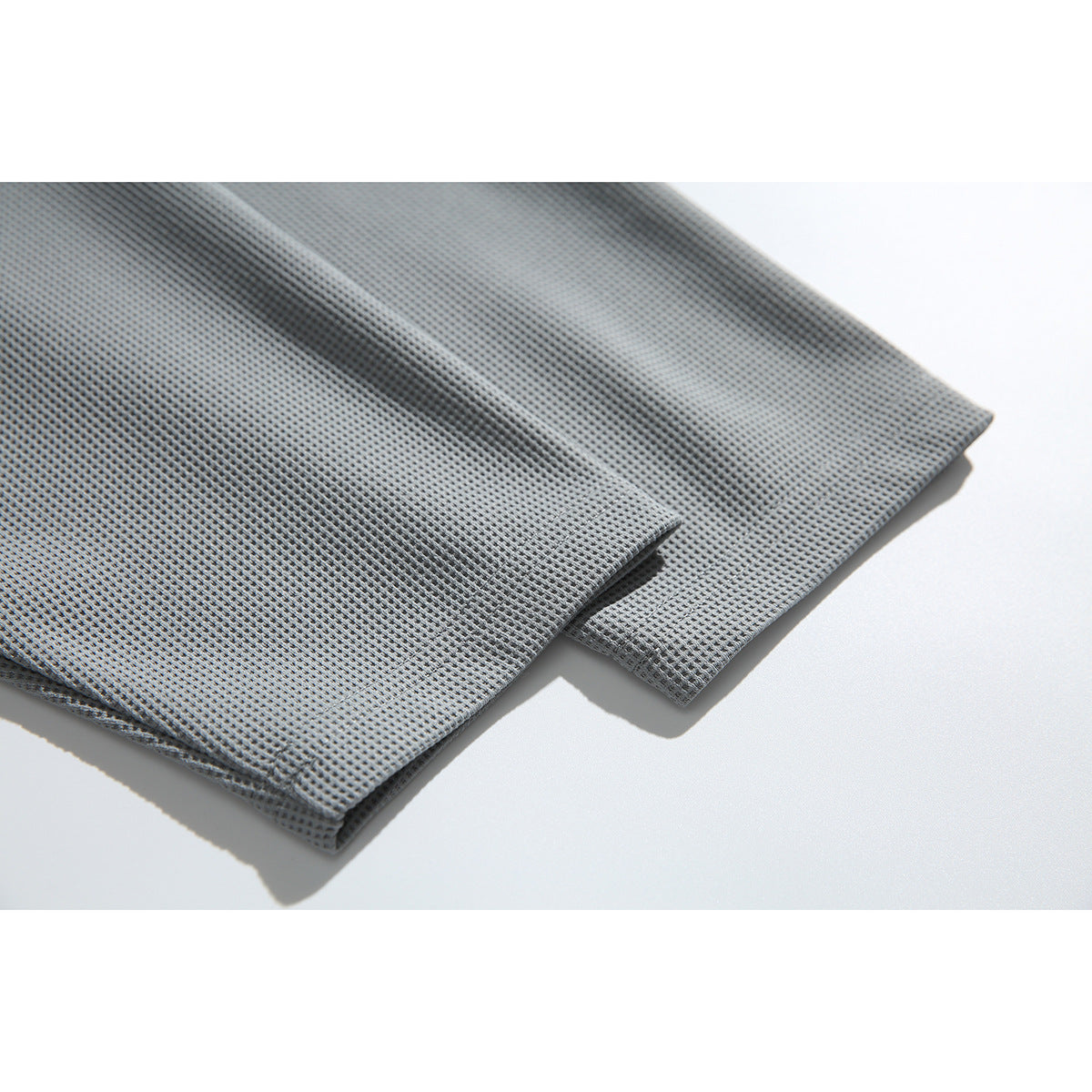 Close-up of folded edges on gray waffle-textured fabric against a white background.