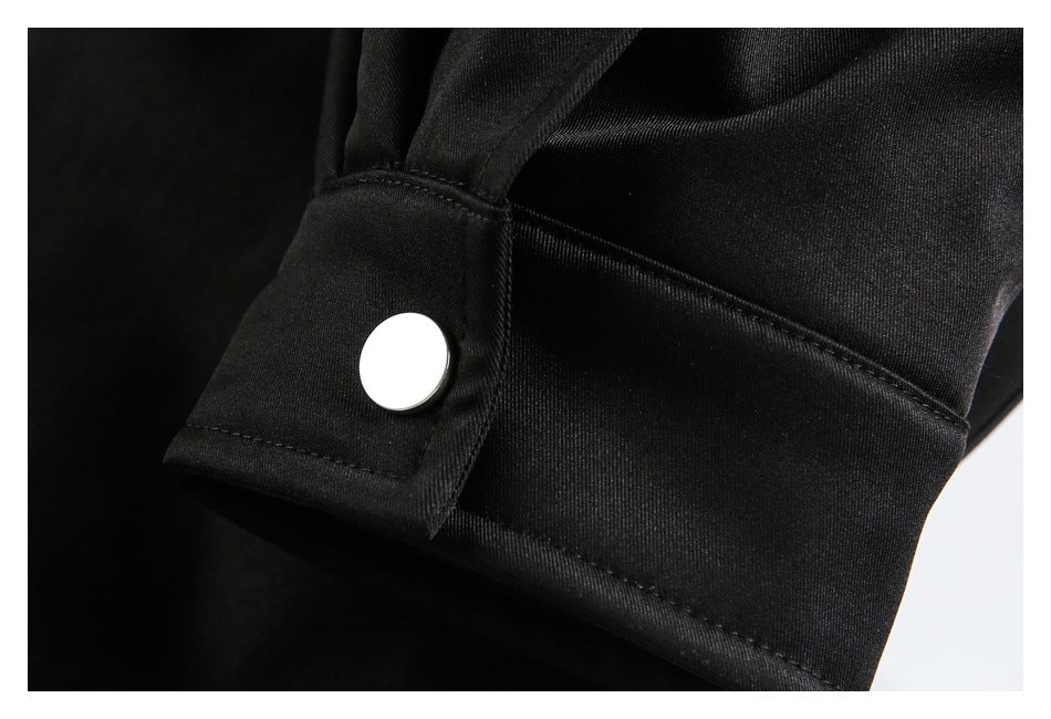 Close-up of a black jacket cuff with a silver snap button and stitched trim.