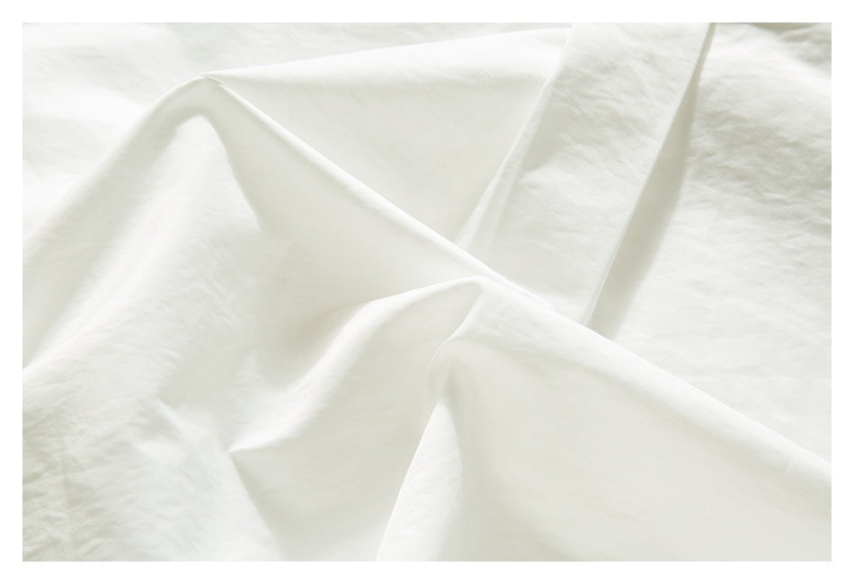 Close-up of white garment fabric arranged in soft folds, showing its smooth surface and drape.