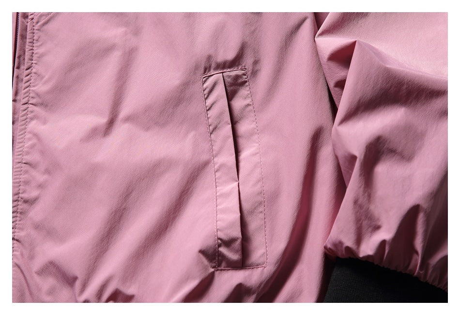 Close-up of a pink jacket's vertical welt pocket, sleeve, and black ribbed cuff.