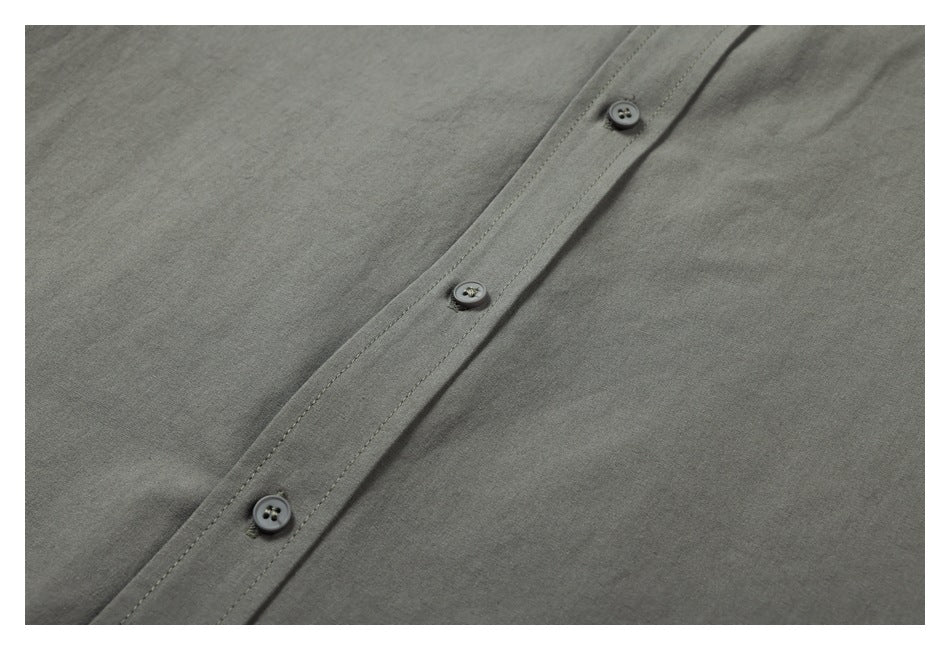 Close-up of three dark buttons and stitching along the dark gray shirt's front placket.