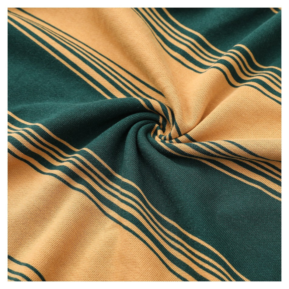 Close-up of the mustard and dark green striped garment fabric gathered to show its drape and texture.