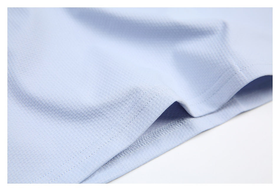 Close-up of the stitched hem on a light blue shirt.